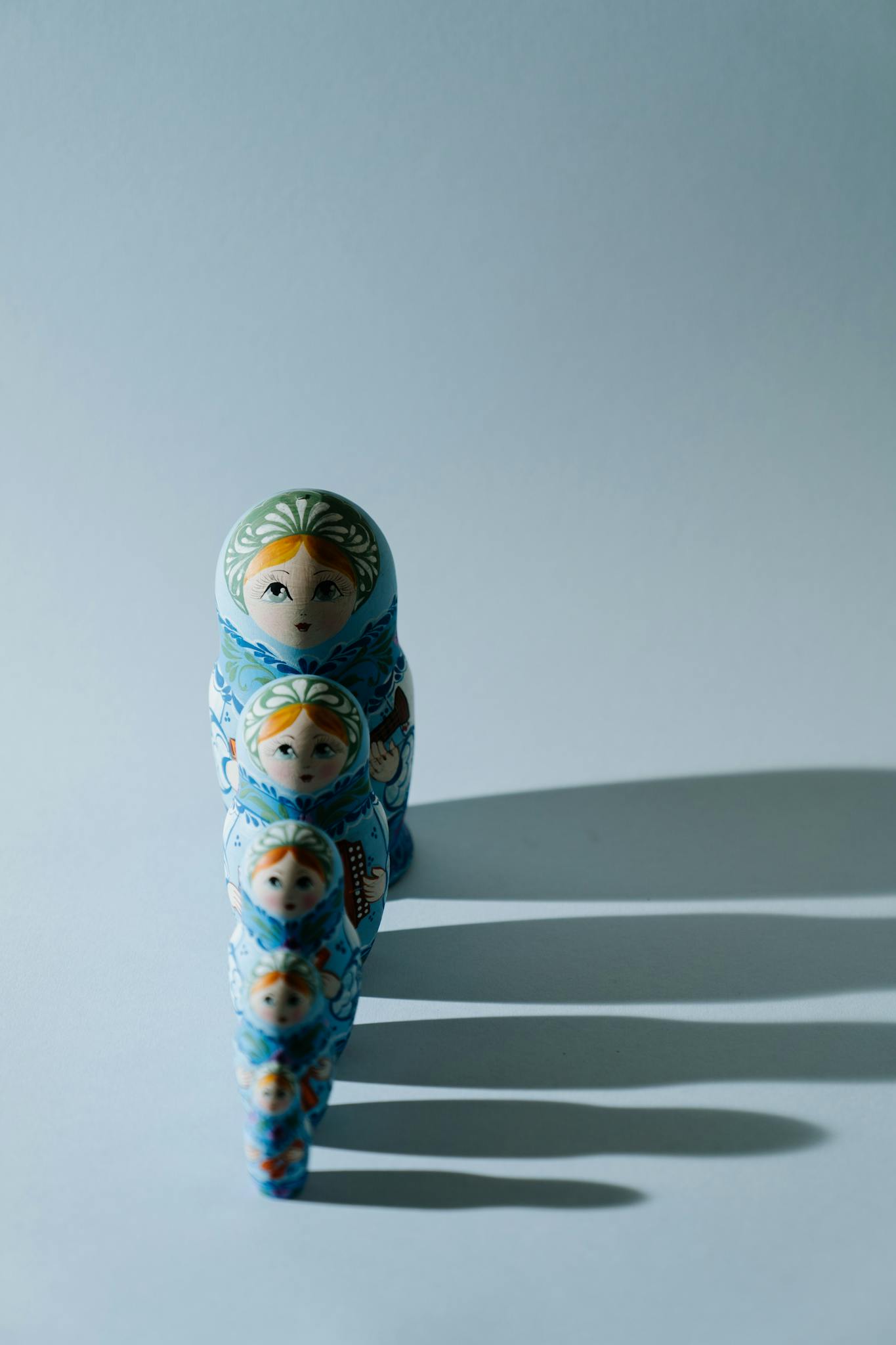Traditional Russian matryoshka nesting dolls in a row against a blue backdrop.
